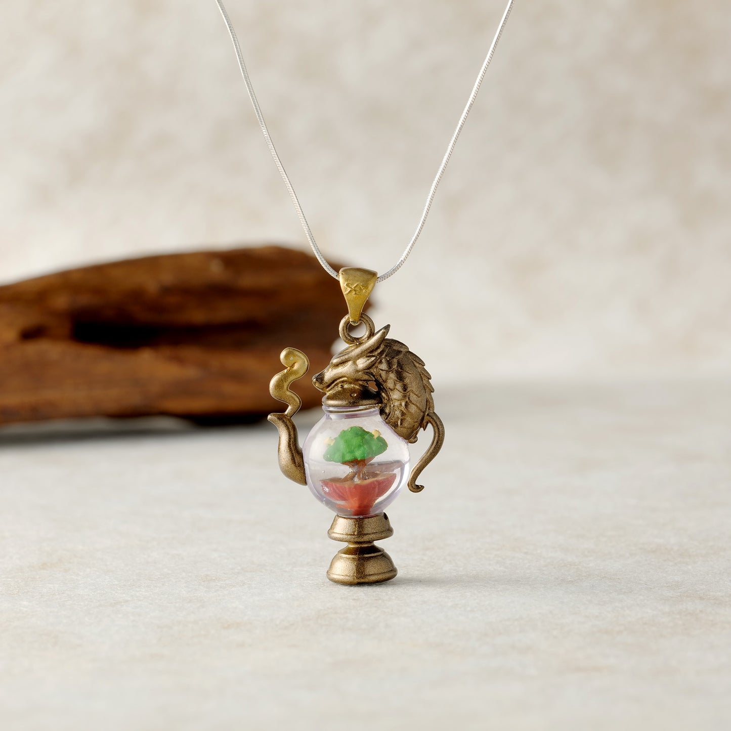 alt="Dragonbrew Teapot Necklace styled with flowers and mystical background"